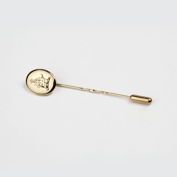 A yellow gold tie pin with a family crest design of a boat.